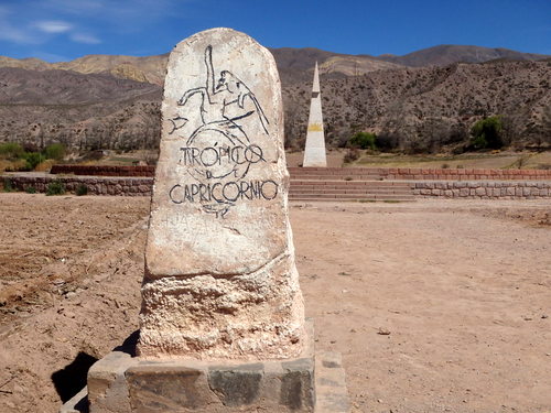 Tropical de Capricornio stone carved sign and the Sun Monument is in the background.